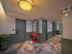 A hotel hallway with green doors, a red bench, and a patterned carpet. - Tonkin Luxury Boutique Hotel & Spa (Hanoi)
