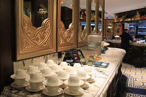 Una cocina de hotel con encimera de mármol, una máquina de café y un chef preparando comida.