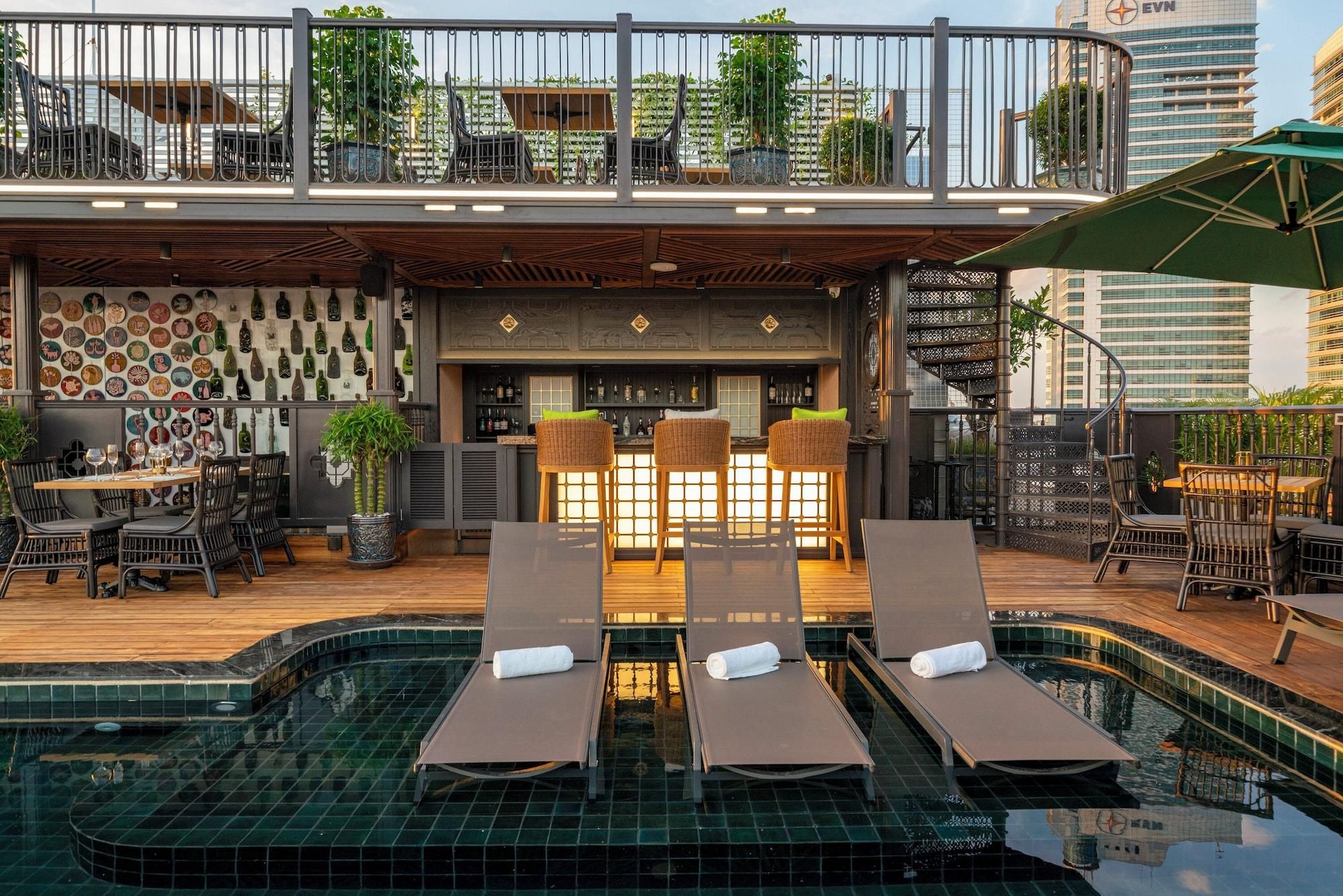 A rooftop bar with a pool, lounge chairs, and a bar area with a wine display.