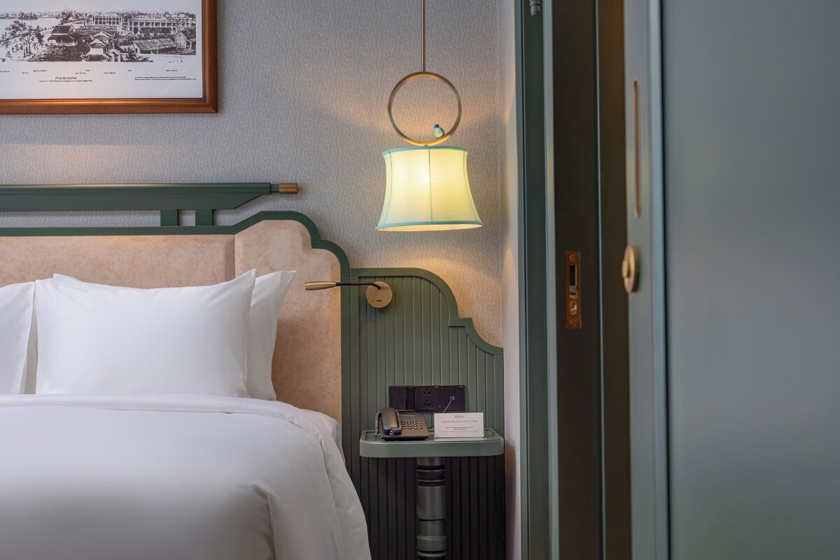 A neatly made bed with white linens in a hotel room.