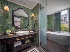 A modern bathroom with green mosaic tiles, a large mirror, a vanity with a sink, and a bathtub. - Tonkin Luxury Boutique Hotel & Spa (Hanoi)