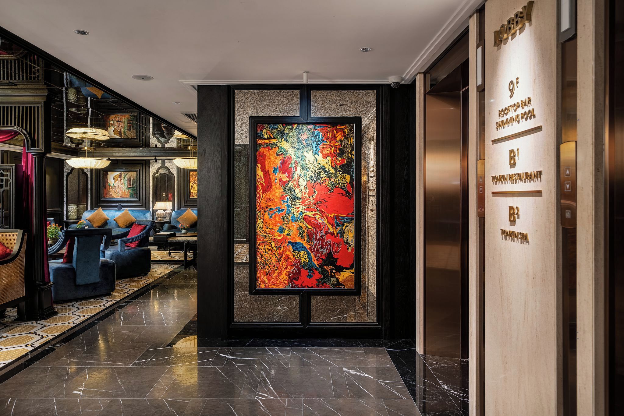 A lobby with a large abstract painting, a reception desk, and a seating area with sofas and tables.