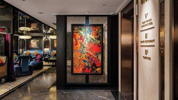 A lobby with a large abstract painting, a reception desk, and a seating area with sofas and tables.