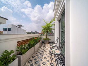A balcony with patterned flooring, potted plants, and two chairs. - Tonkin Luxury Boutique Hotel & Spa (Hanoi)