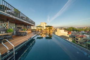 A rooftop pool with a wooden deck, outdoor seating, and a view of surrounding buildings. - Tonkin Luxury Boutique Hotel & Spa (Hanoi)
