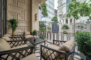 Un balcón con mobiliario exterior, una planta en maceta y vistas a un edificio histórico.