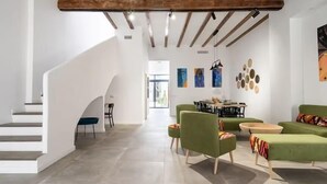 A spacious living area with a staircase, green sofas, a dining table, and artwork on the walls. - Villa Ramon (Valencia)