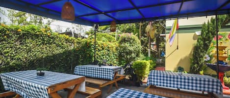 An outdoor patio with checkered tablecloths, wooden tables, and chairs.