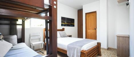 A room with a bed, a chair, a wooden wardrobe, and a television.
