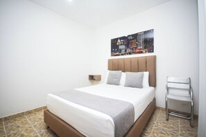 Ein Hotelzimmer mit Bett, Nachttisch, Wandlampe und einem Stadtbild.