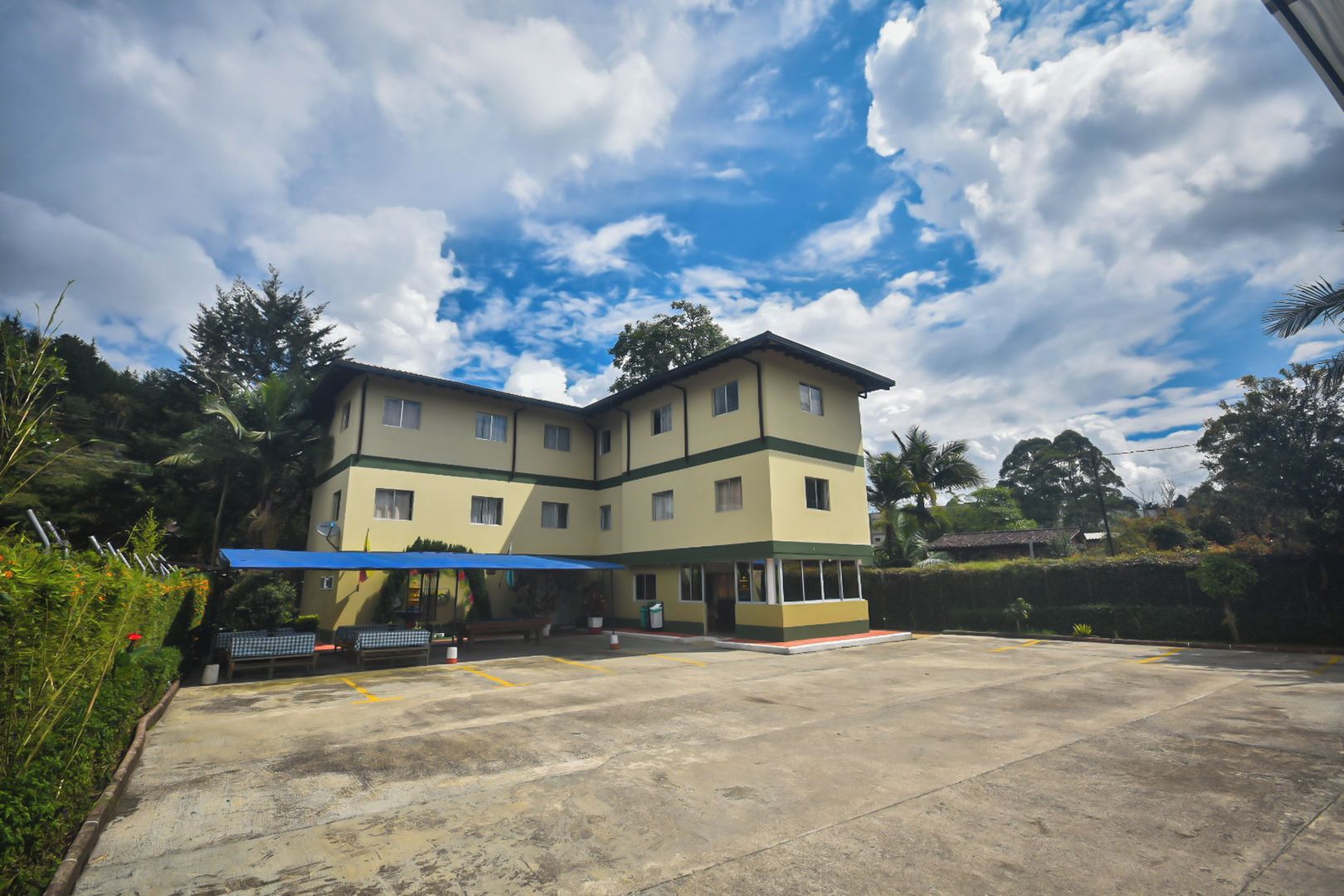 A multi-story hotel with a flat roof, a covered outdoor seating area, and a parking lot.