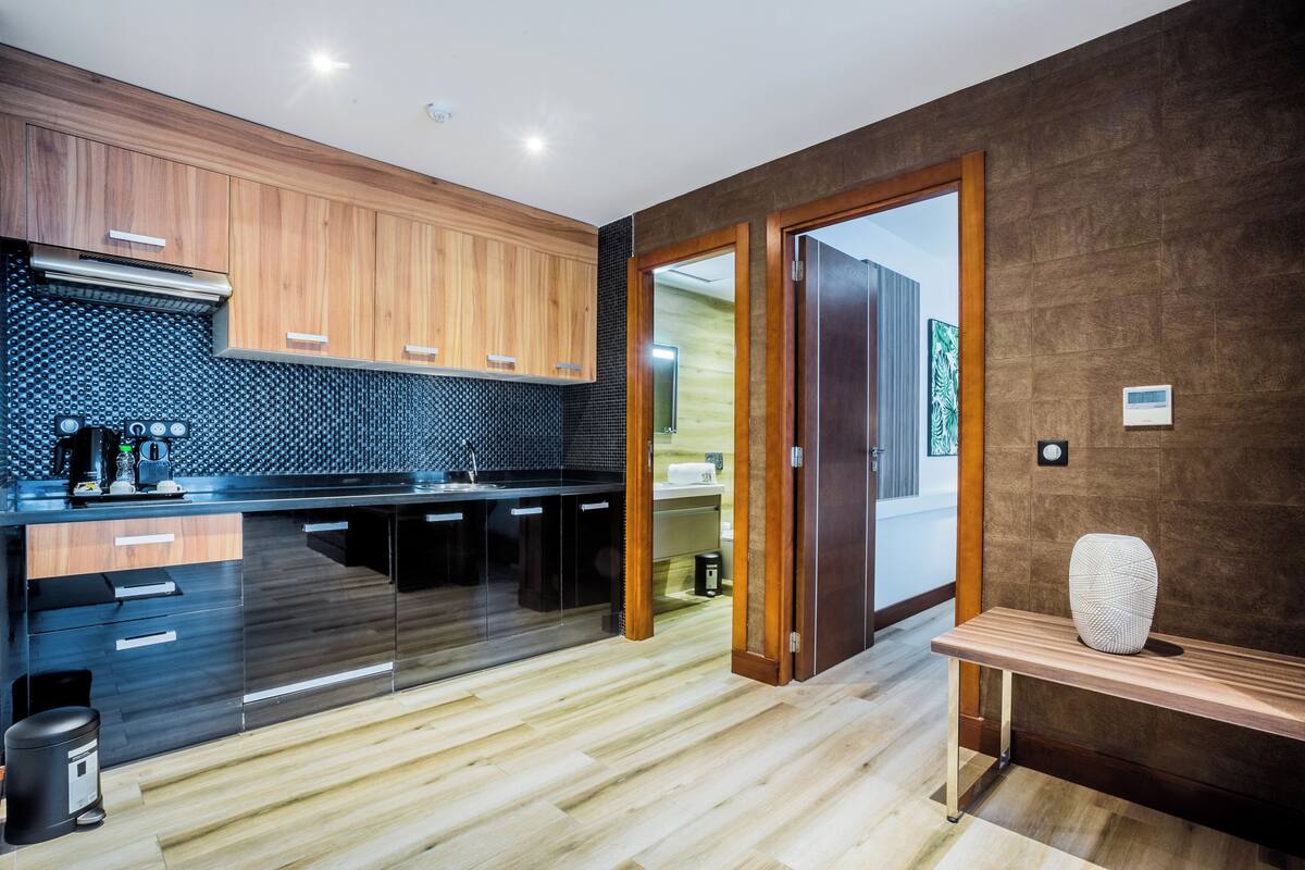 A modern kitchen with wooden cabinets, a black countertop, and a wooden bench.