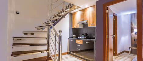 Una cocina moderna con una escalera de madera, estufa empotrada y una pequeña isla.