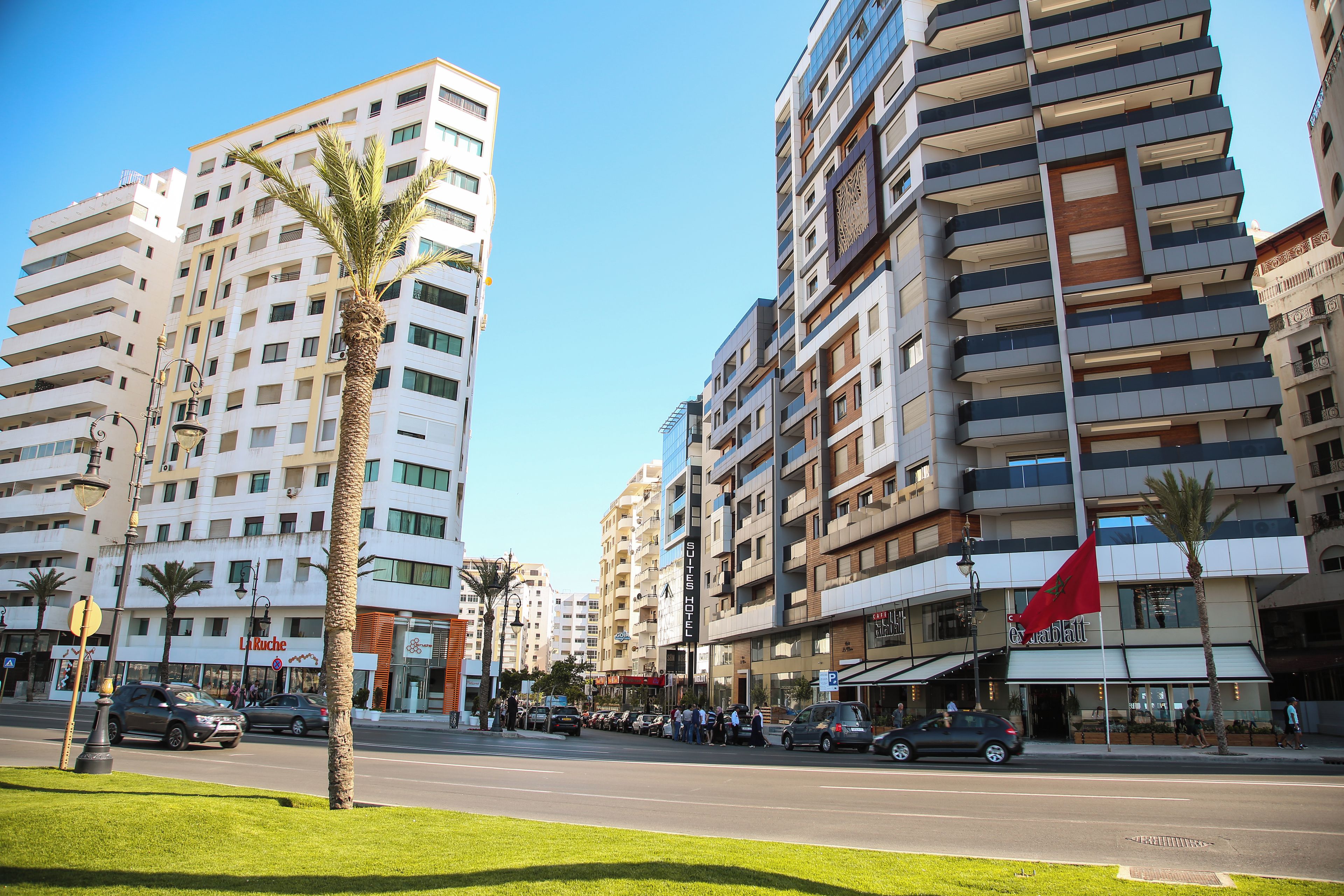 A multi-story hotel with balconies, a flag, and a street in front.