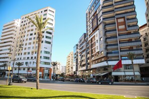 A multi-story hotel with balconies, a flag, and a street in front. - Sbn Suites Hotel (Tangier)