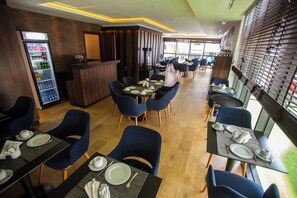 A restaurant with tables set for dining, a beverage dispenser, and a reception area. - Sbn Suites Hotel (Tangier)