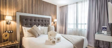 Ein modernes Hotelzimmer mit einem großen Bett, Holzwandverkleidung und Blick auf die Stadt durch große Fenster.