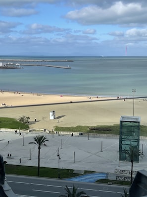 A beach with a clear view of the ocean, a pedestrian walkway, and a glass structure. - Sbn Suites Hotel (Tangier)