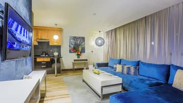 A modern living room with a blue sofa, a white coffee table, and a TV mounted on the wall.
