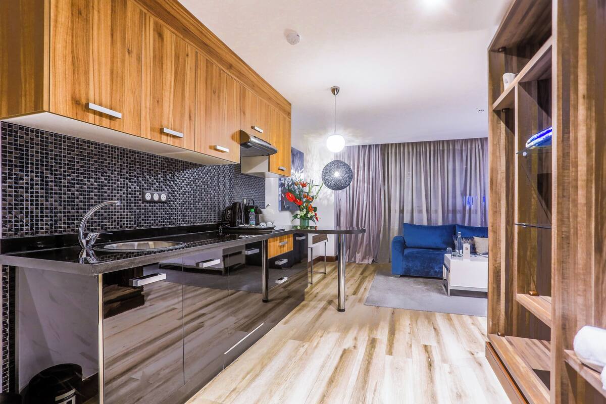 A modern kitchen with wooden cabinets, a black tiled backsplash, and stainless steel appliances.