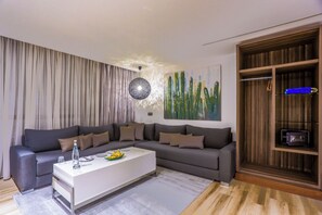 A modern living room with a sectional sofa, a white coffee table, and a wooden cabinet with a microwave. - Sbn Suites Hotel (Tangier)