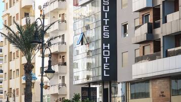 A hotel with a modern facade, balconies, and a visible sign for 'SQUITES HOTEL.'