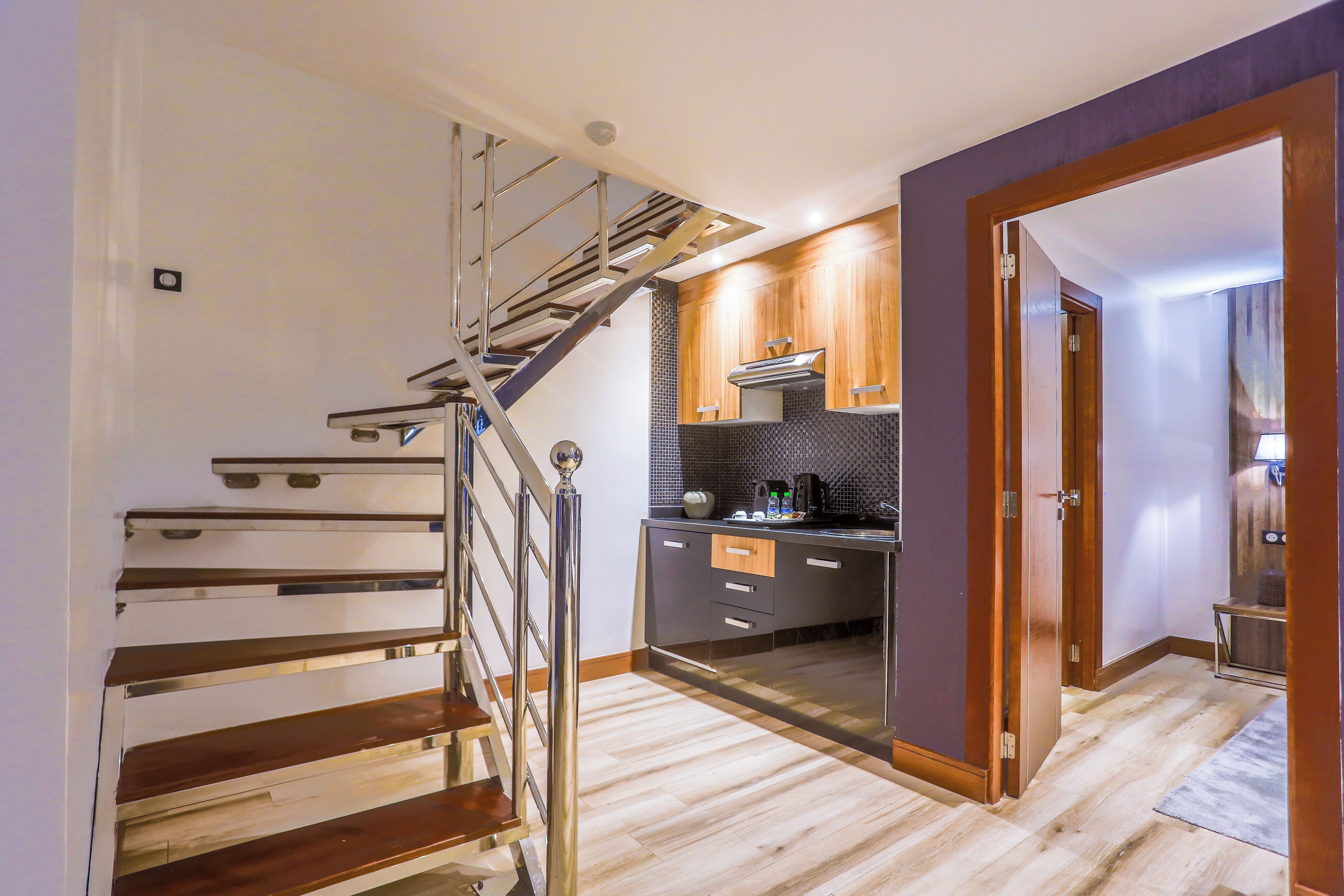 A modern kitchen with a wooden staircase, a built-in stove, and a small island.