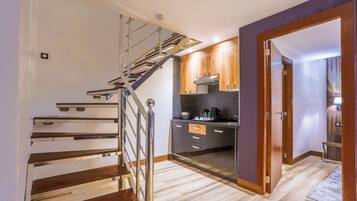 A modern kitchen with a wooden staircase, a built-in stove, and a small island.