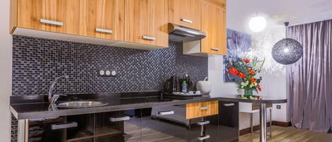 A modern kitchen with wooden cabinets, a black tiled backsplash, and stainless steel appliances.