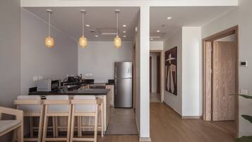 A modern kitchen with a dining area, stainless steel appliances, and pendant lighting.