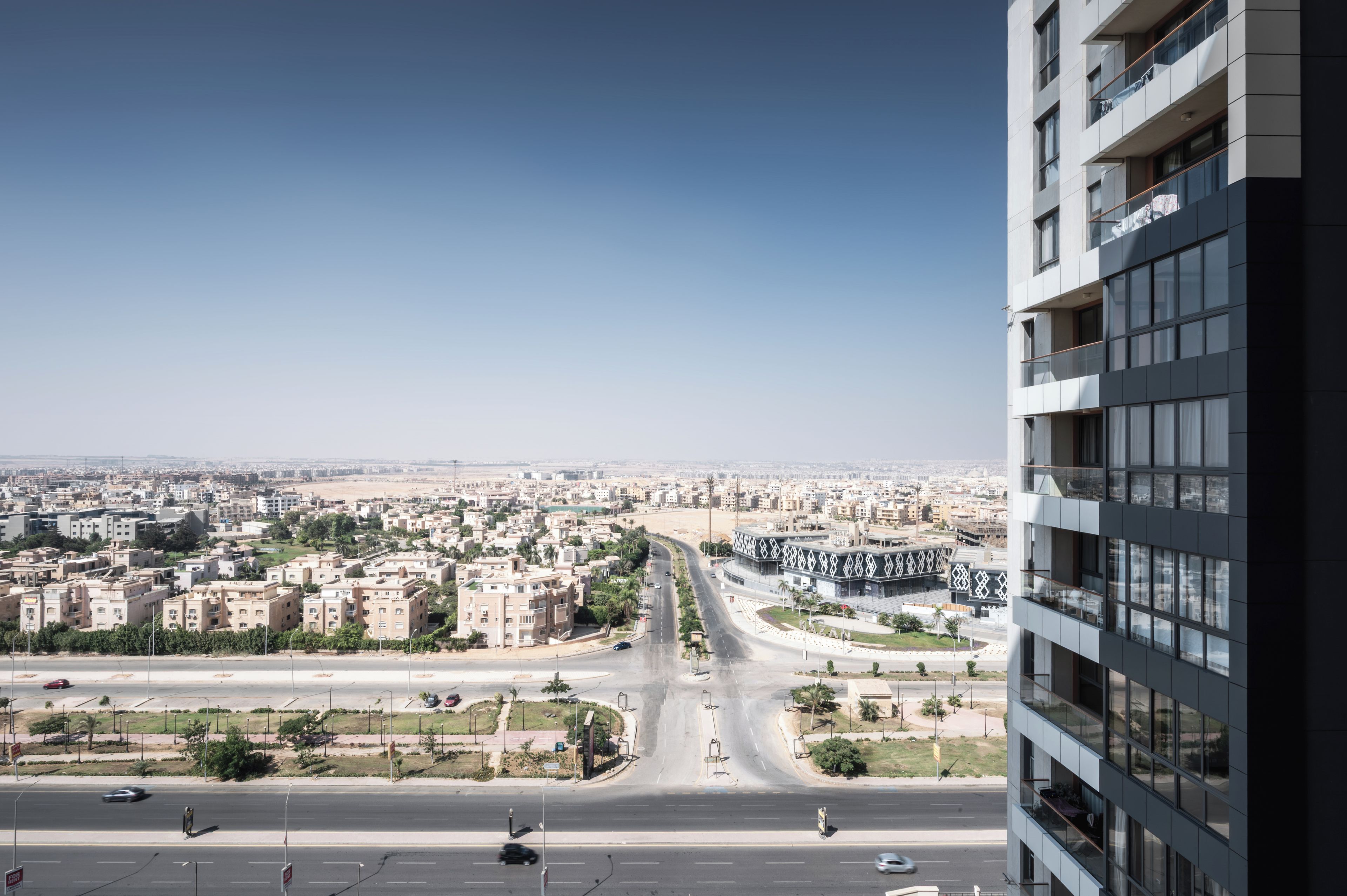 Un immeuble de grande hauteur offrant une vue sur le paysage urbain, notamment sur une route et des immeubles d’habitation.