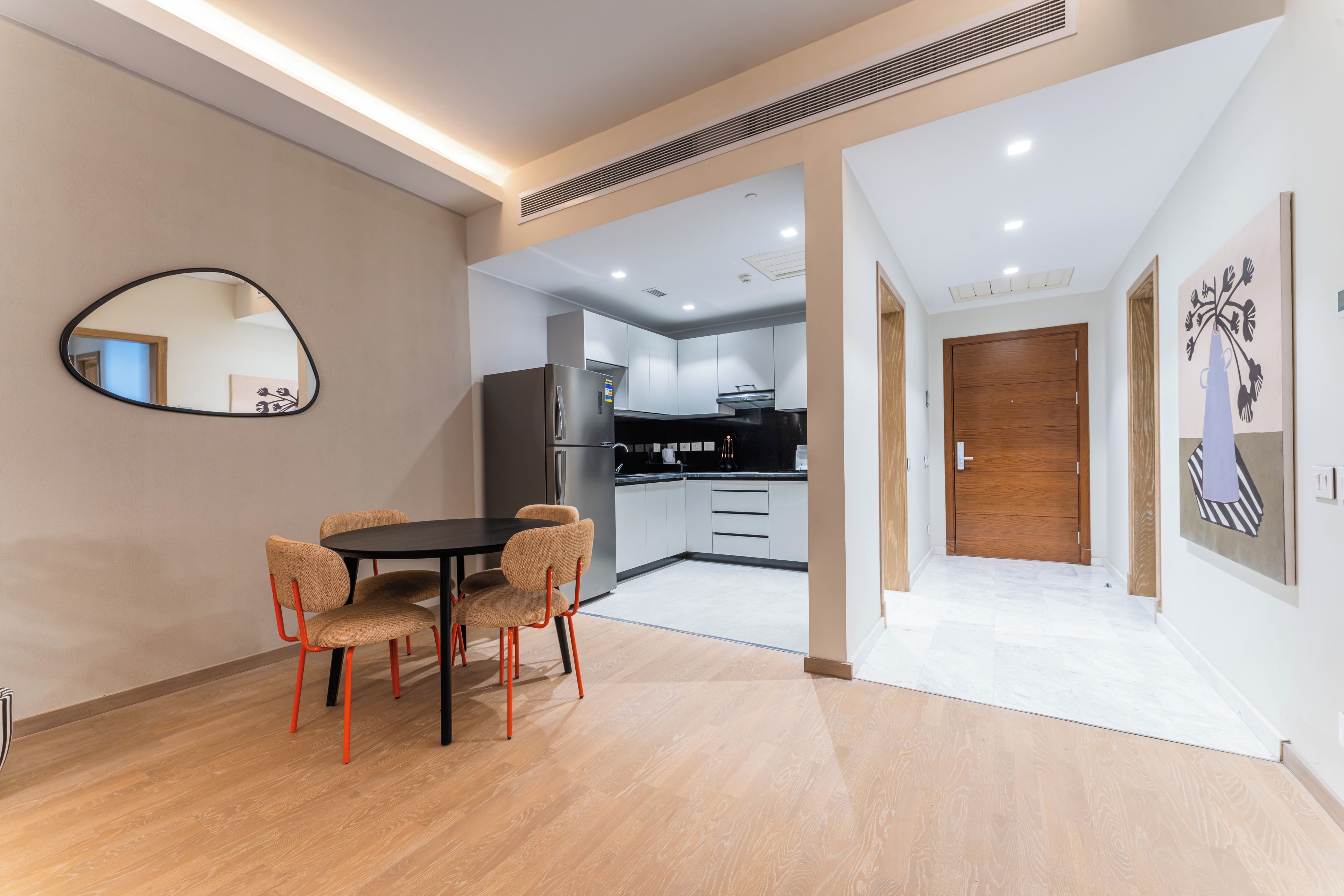 A modern kitchen with white cabinets, a black countertop, and a stainless steel refrigerator.