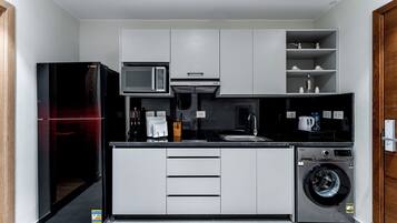 Una cocina moderna con refrigerador, microondas, lavamanos y lavadora.