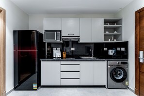 A modern kitchen with a refrigerator, microwave, sink, and washing machine.