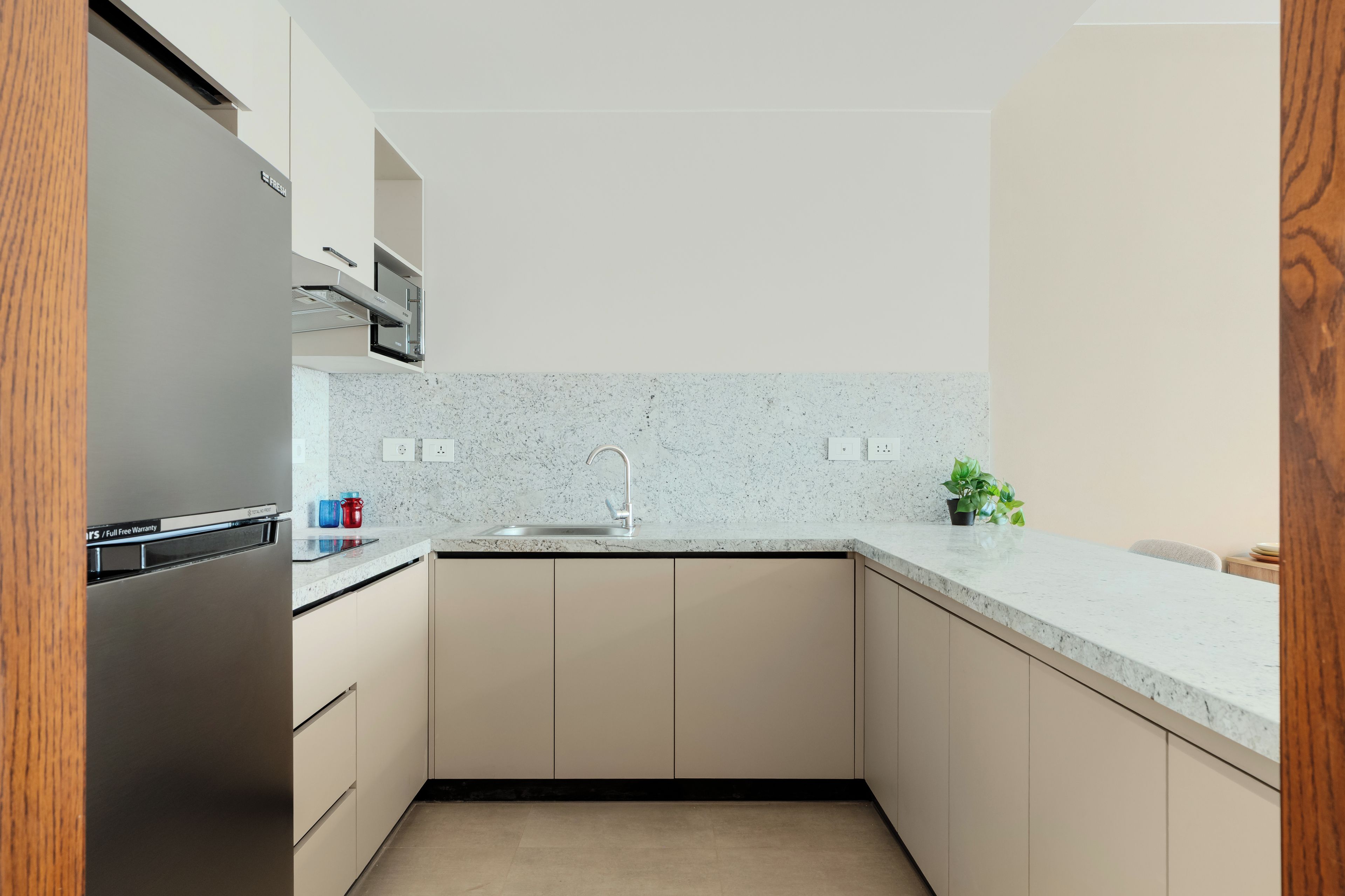A modern kitchen with a stainless steel refrigerator, a microwave, a sink, and a countertop.
