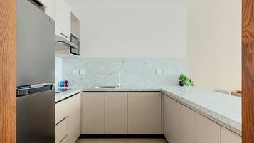 A modern kitchen with a stainless steel refrigerator, a microwave, a sink, and a countertop.