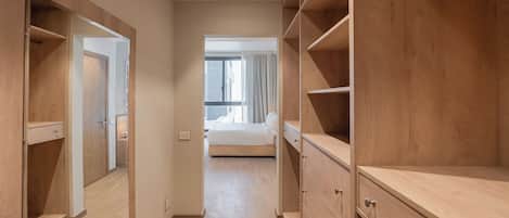Un pasillo que conduce a un dormitorio con una cama, un armario y un aparador.