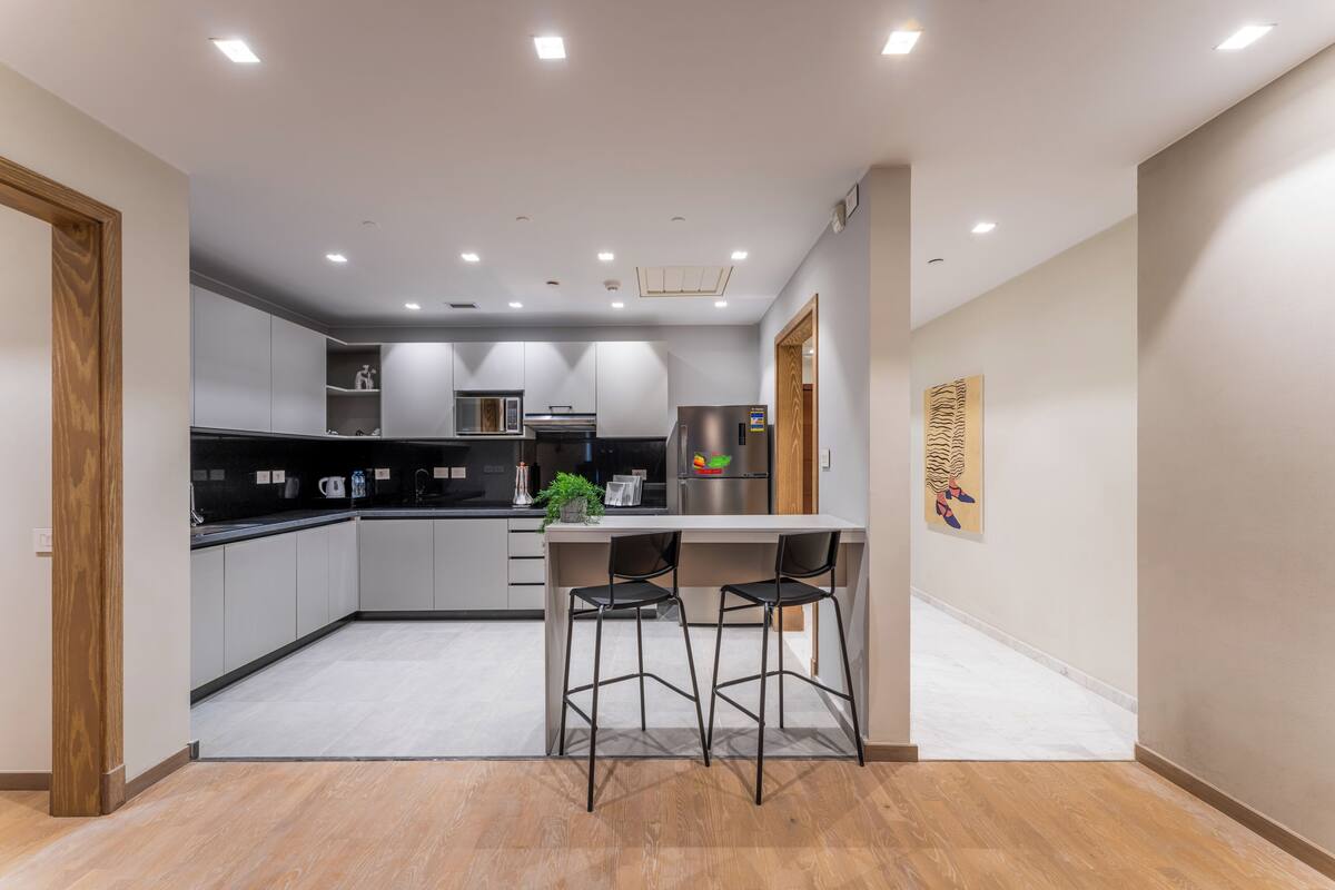 Una cocina moderna con una isla central, taburetes de bar y electrodomésticos integrados.