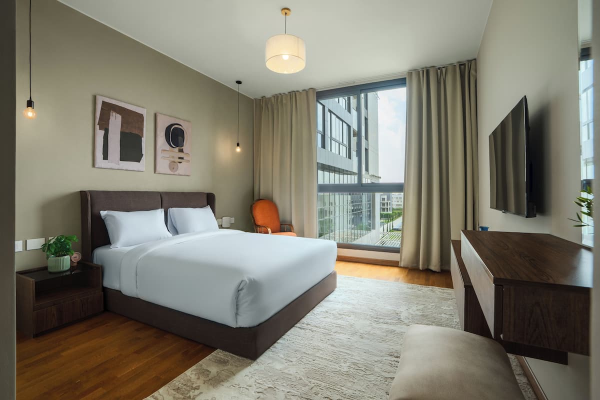Un dormitorio de hotel moderno con una cama grande, un escritorio, una silla y un televisor.