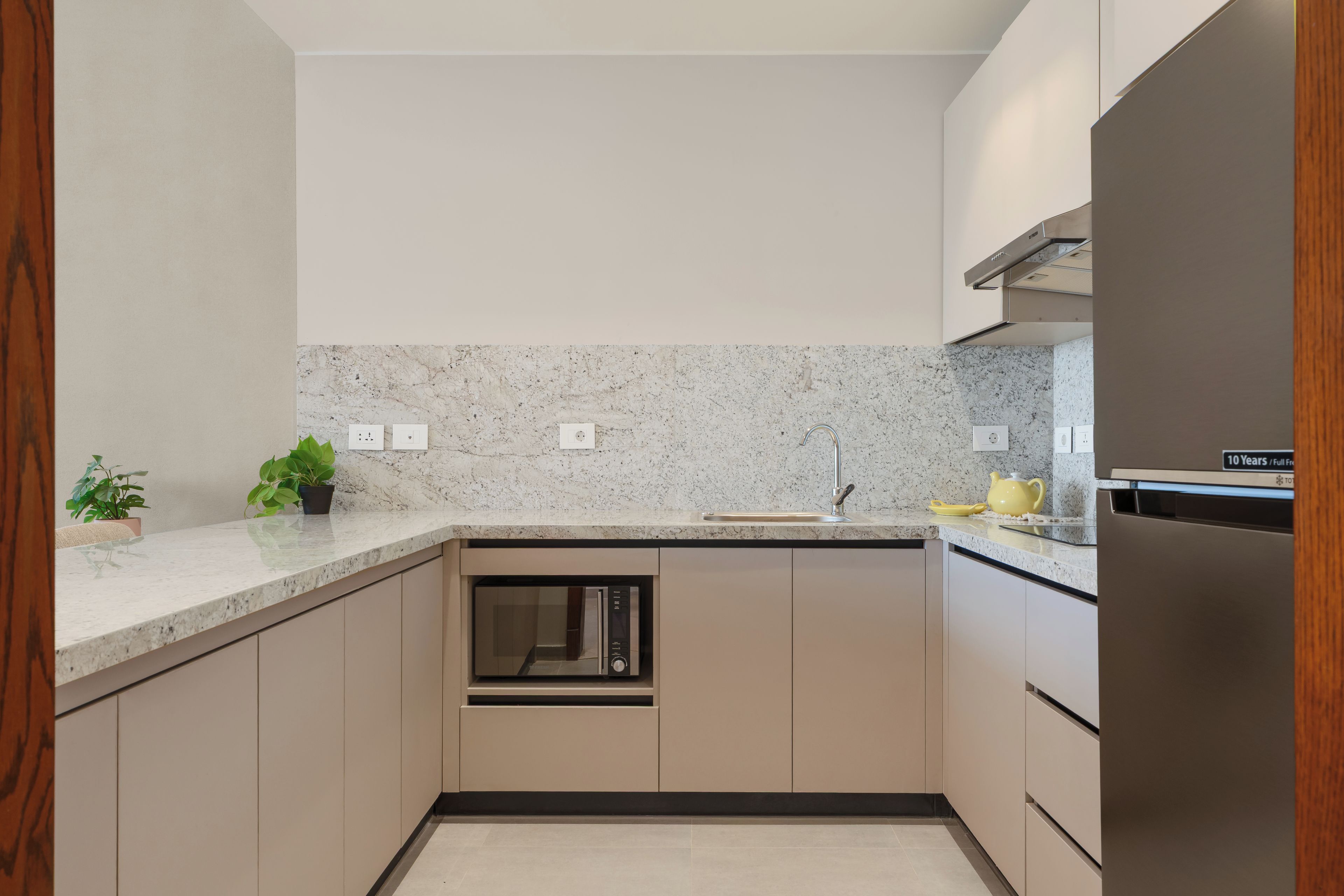 A modern kitchen with built-in appliances, a granite countertop, and wooden cabinetry.