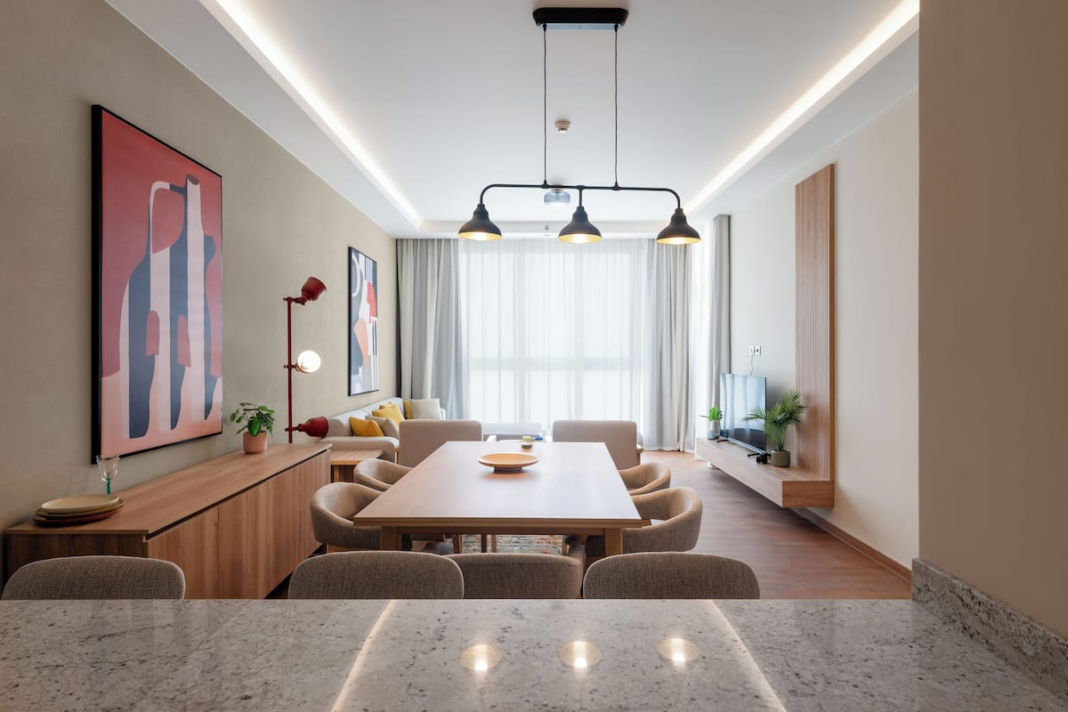 Un comedor moderno con una mesa de madera, sillas, iluminación colgante y obras de arte en las paredes.