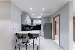 Una cocina moderna con una isla central, taburetes de bar y un refrigerador.