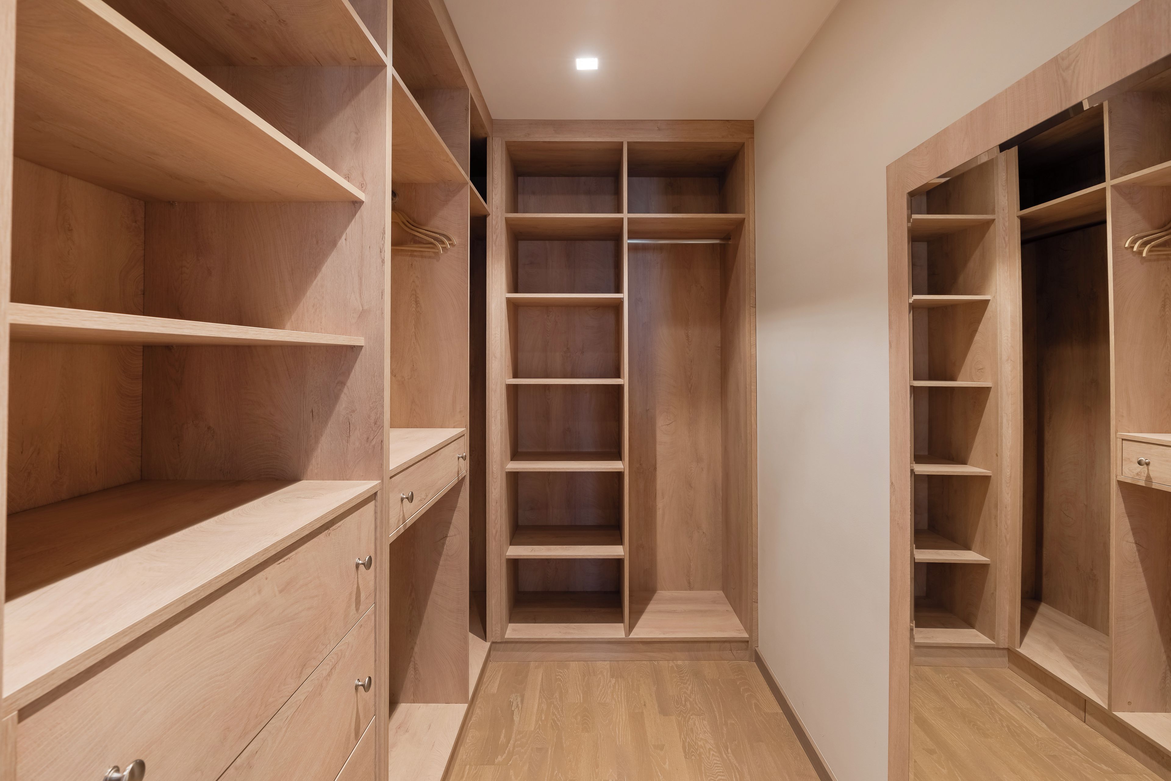 A walk-in closet with multiple wooden shelves and drawers.