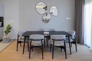 A modern dining area with a rectangular table, six chairs, and three wall-mounted mirrors.