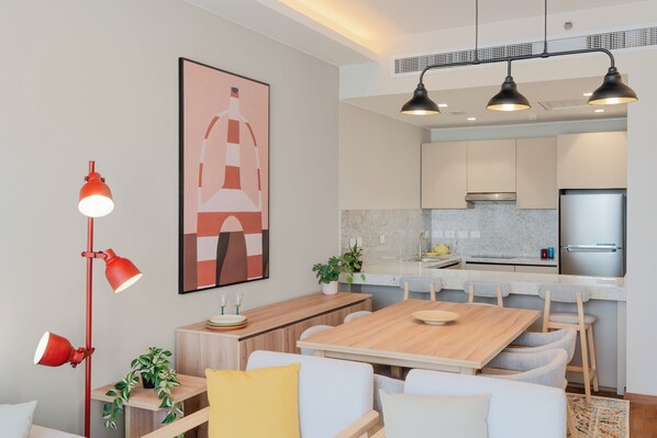 Una cocina moderna con un refrigerador de acero inoxidable, una mesa de comedor de madera y una lámpara colgante roja.