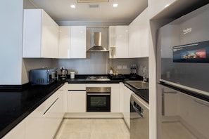 A modern kitchen with white cabinets, a black countertop, stainless steel appliances, and a built-in oven.