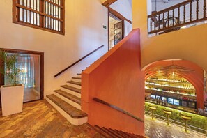 Un escalier avec une rampe en bois menant à un espace bar équipé de tabourets et doté d’un sol carrelé.