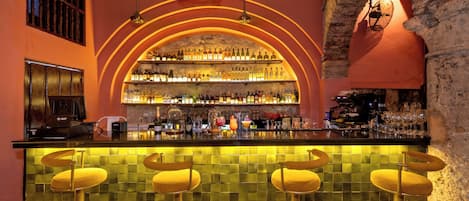 A bar with a tiled backsplash, a wine rack, and a coffee machine.