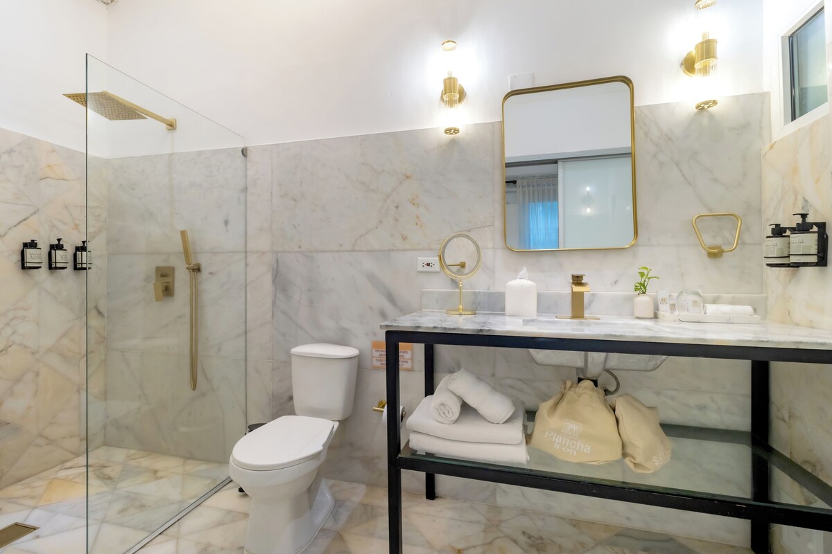 Een moderne badkamer met een douche met glazen wand, een wit toilet en een vloer van marmertegels.