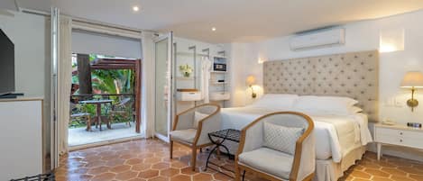 Una habitación de hotel con cama, dos sillas, una mesita de noche y una pequeña mesa.